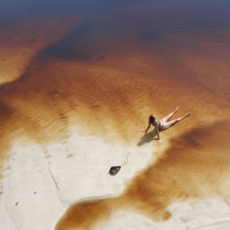 A person sunbathing on a sandy river beach
