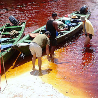 People by the small boats in the red water