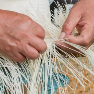 Closeup on the hands of a person weaving a sombrero